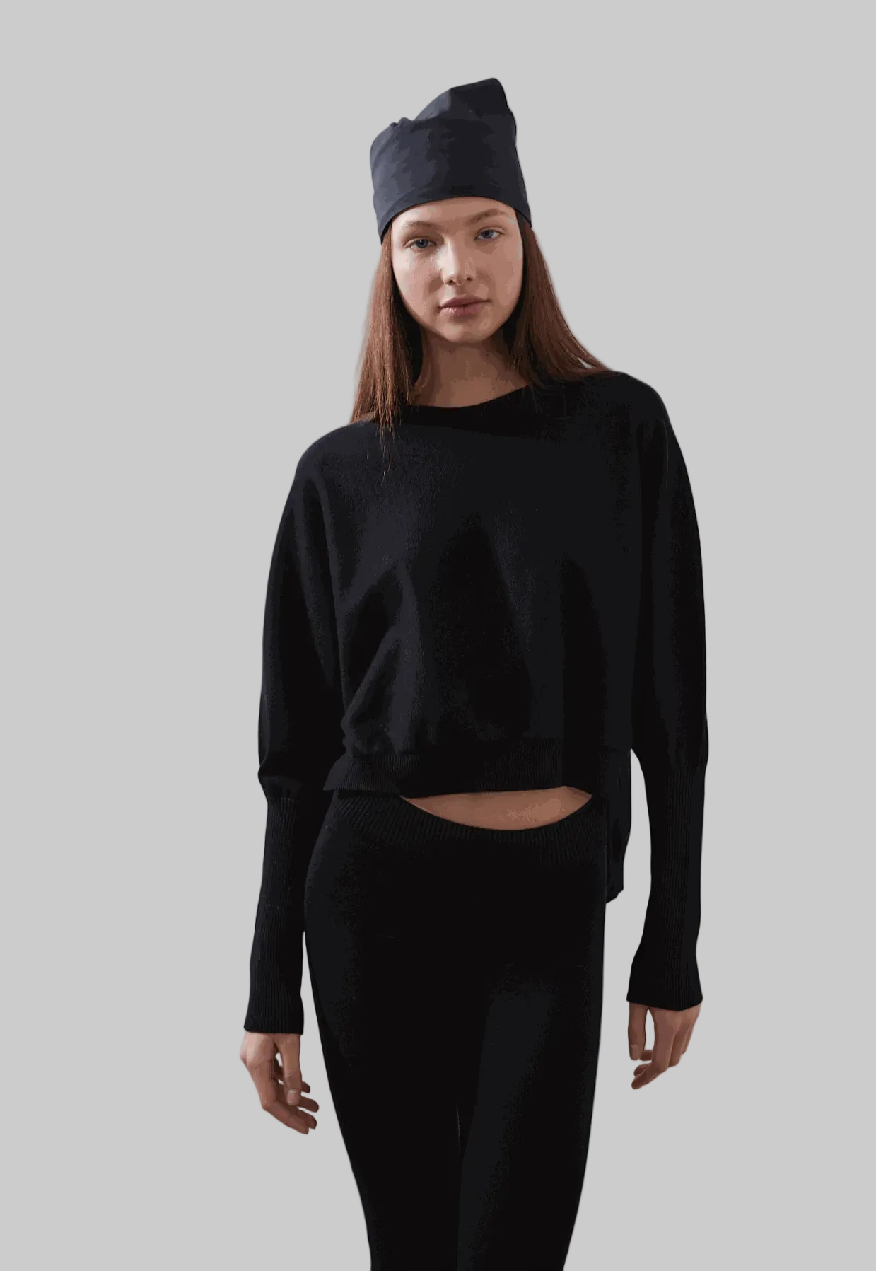 ARMERS Pullover in black with drop sleeves and high-low bodice, modeled by woman in black leggings.